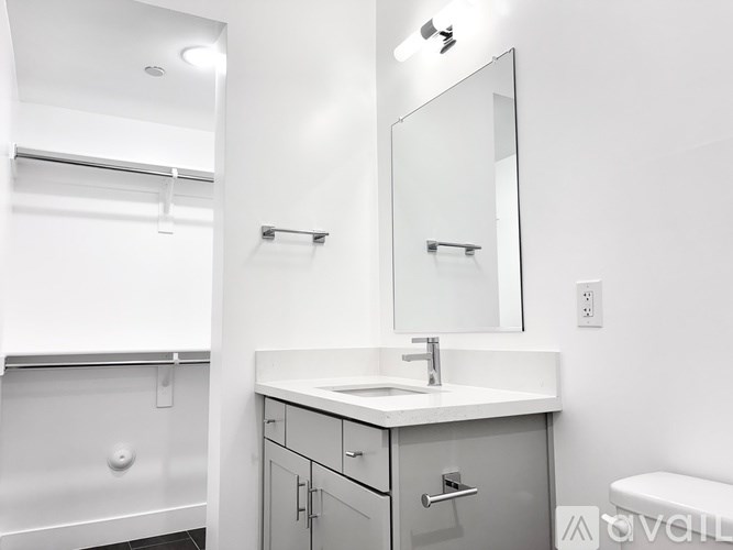 A white bathroom with a sink, mirror, and towel rack.