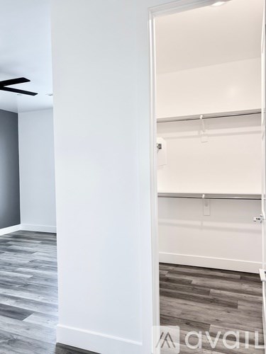 A white door is open to a room with a wooden floor.