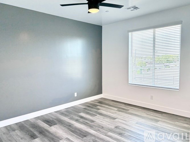 A room with a ceiling fan and a window with blinds.
