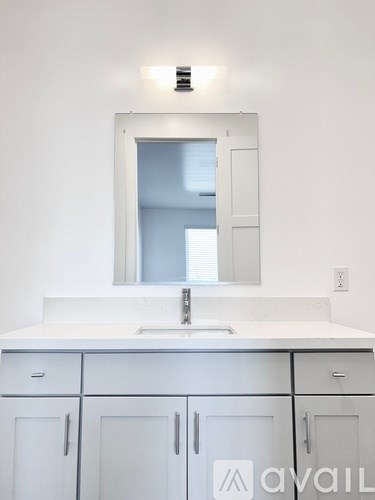 A white bathroom vanity with a sink and mirror.