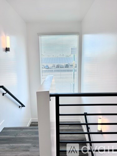 A staircase with a black railing and a white wall.
