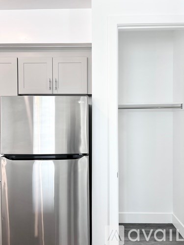 A stainless steel refrigerator with a black shelf sits next to a white wall.