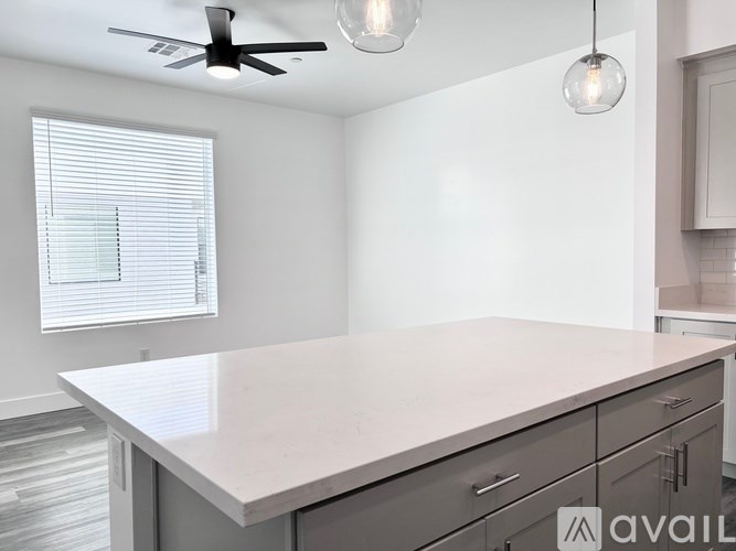 A kitchen with a white countertop and a ceiling fan.