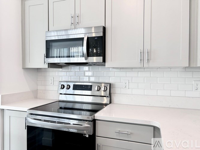 A kitchen with white cabinets and a stainless steel oven and microwave.