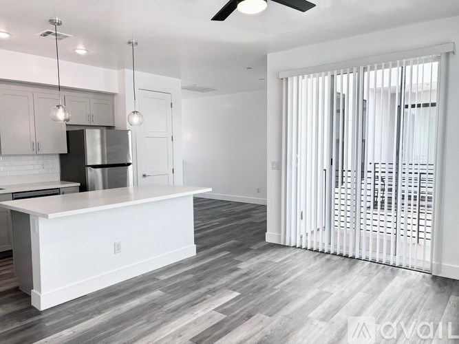 A modern kitchen with a white island and wooden flooring.