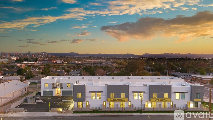 A modern building with a parking lot in front is lit up with yellow lights.