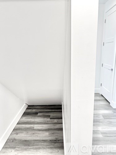A hallway with a white door and wooden flooring.