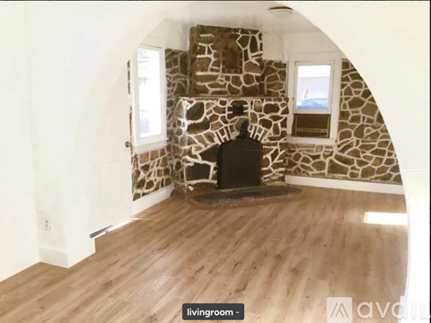 A stone fireplace in a room with wooden floors and white walls.