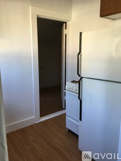 A white fridge in a room with a door open.