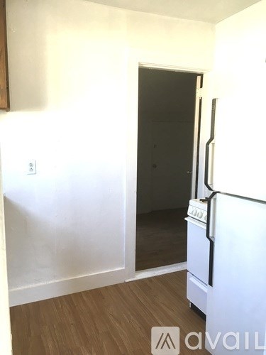 A white fridge in a room with a door and a mirror.