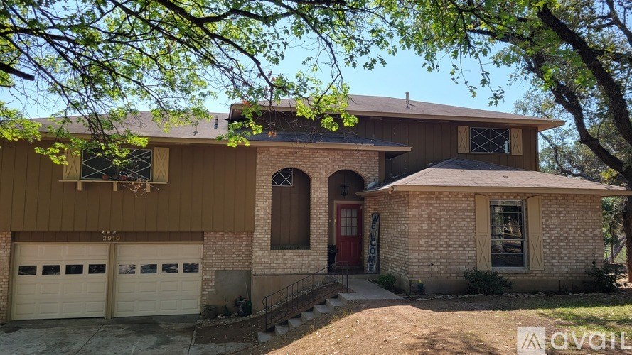 A house with a red door and a brown garage door is for sale.