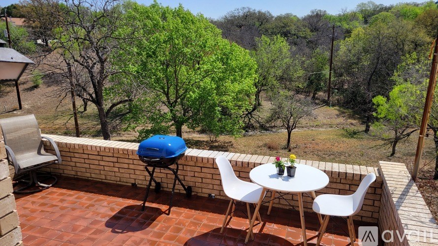 A patio with a table and chairs overlooking a green landscape.
