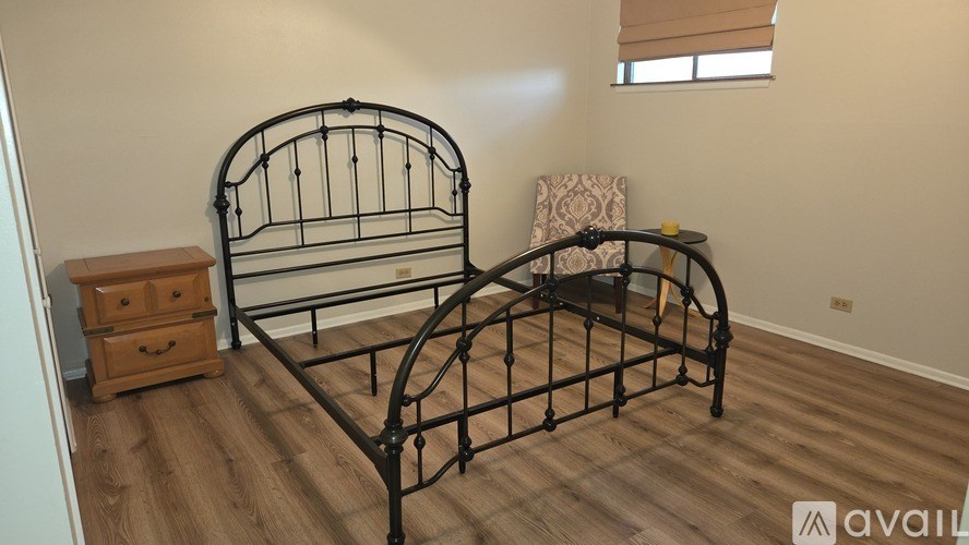A black metal bed frame with a wooden chest beside it in a room.