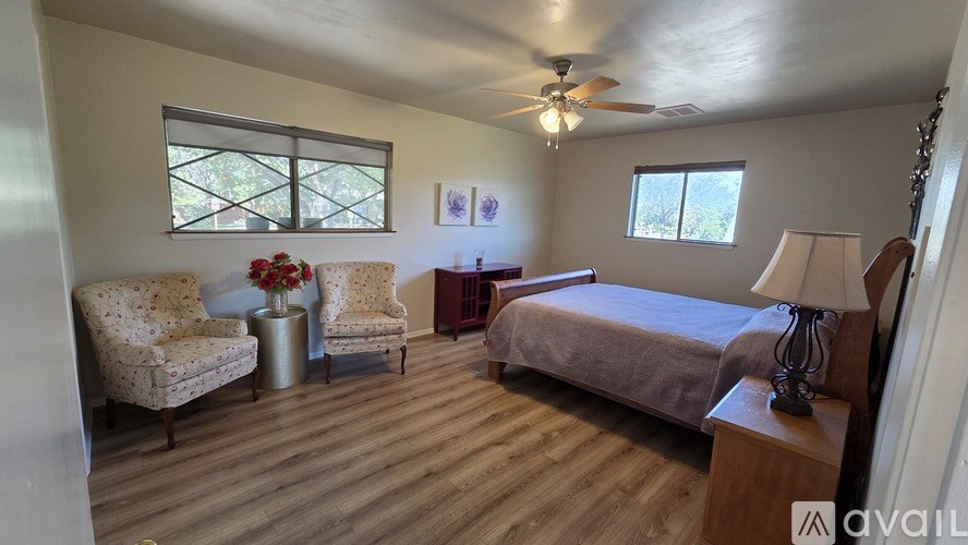 A living room with a black leather couch and a red rug.