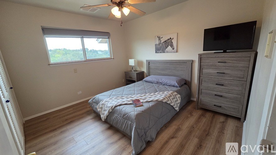 A bathroom with a toilet, a shower curtain, and a black mat.