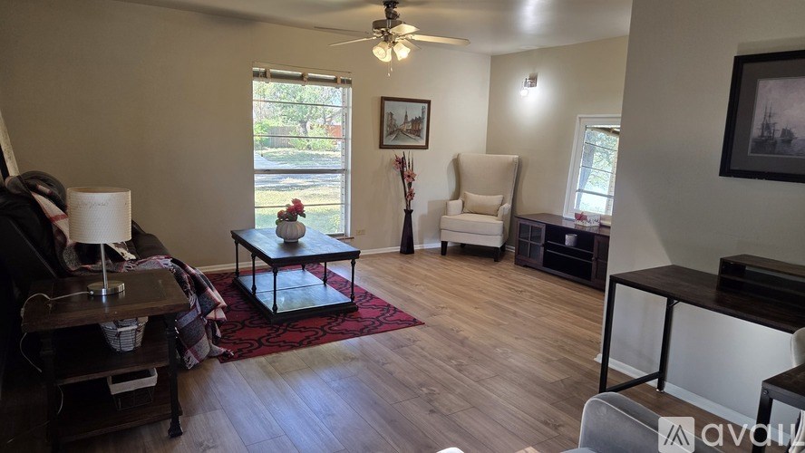 A living room with a black couch, a fireplace, and a ceiling fan.