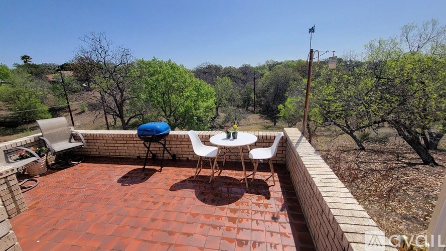 A patio with a table and chairs overlooking a green landscape.