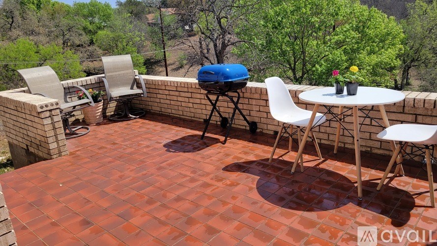 A patio with a table, chairs, and a grill.