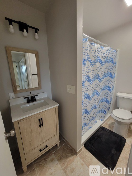 A bathroom with a sink, toilet, and a shower curtain with a blue pattern.