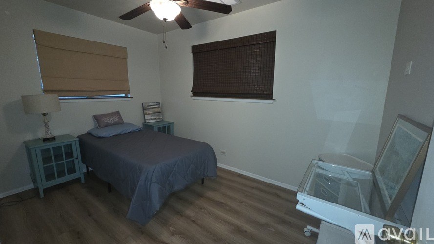 A bedroom with a bed, nightstand, and window with blinds.