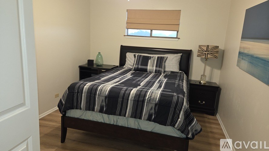 A bedroom with a bed, nightstand, and a painting on the wall.