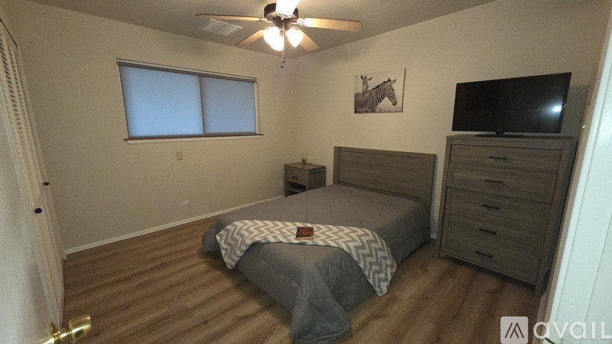 A bedroom with a bed, dresser, and television.