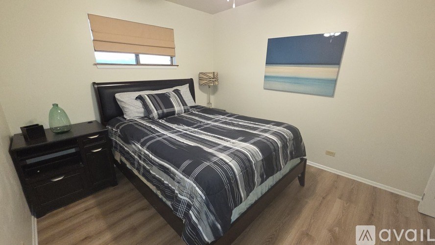 A bedroom with a bed, nightstand, and a painting on the wall.