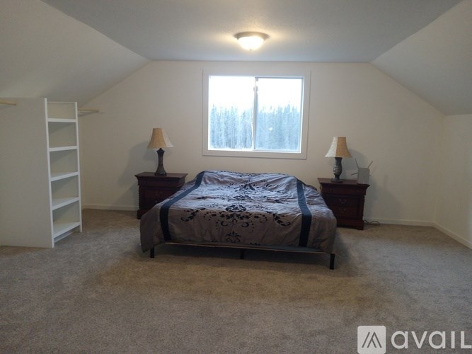 A bedroom with a bed, two lamps, and a window.