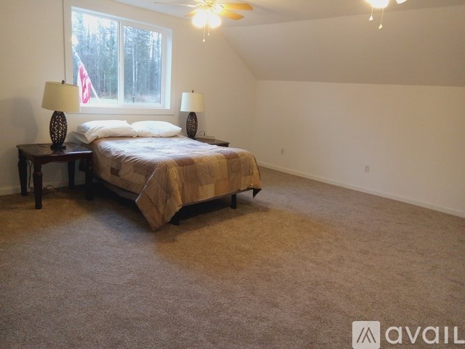 A bedroom with a bed, two lamps, and a window.