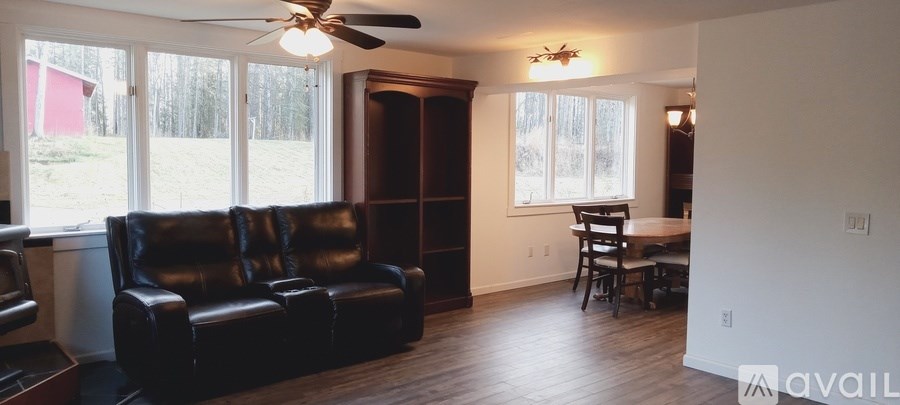 A living room with a black leather couch and a ceiling fan.