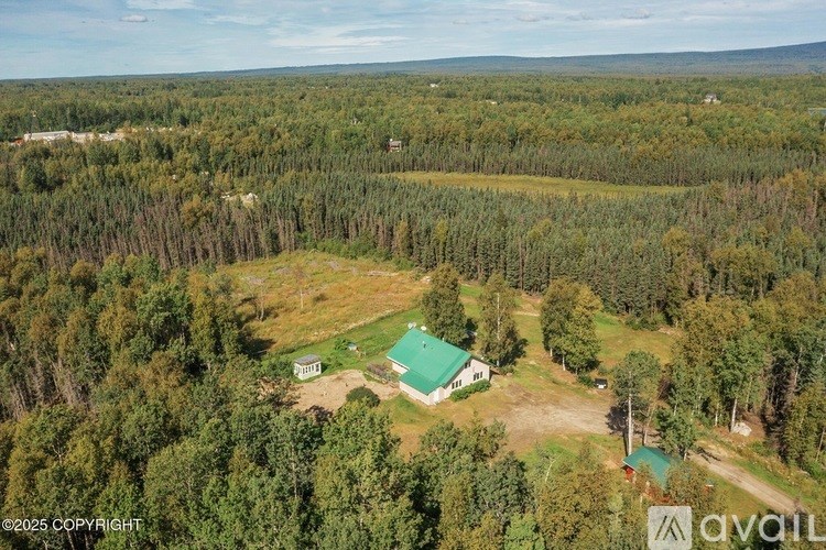 A bird's eye view of a property with a green house and a fenced area.