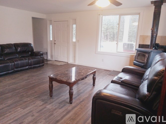 A living room with a black leather couch, a wooden coffee table, and a fireplace.