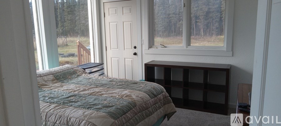 A bedroom with a bed, window seat, and a door.