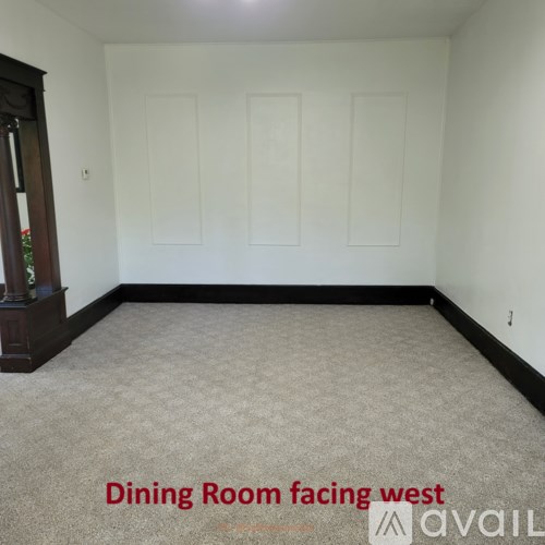 A dining room with a carpeted floor and white walls.