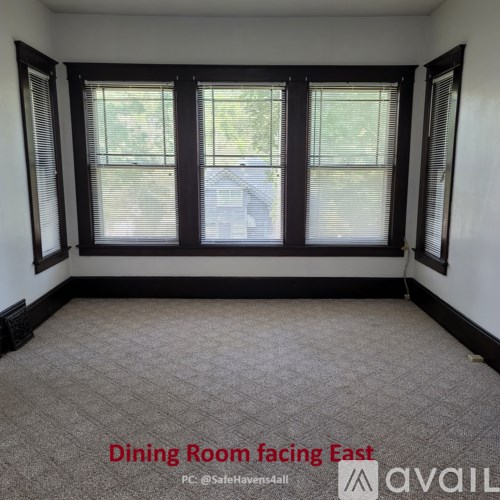 A dining room with a carpeted floor and three windows.