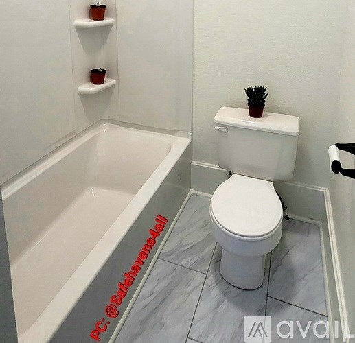 A white toilet with a plant on top sits in a bathroom with a bathtub.