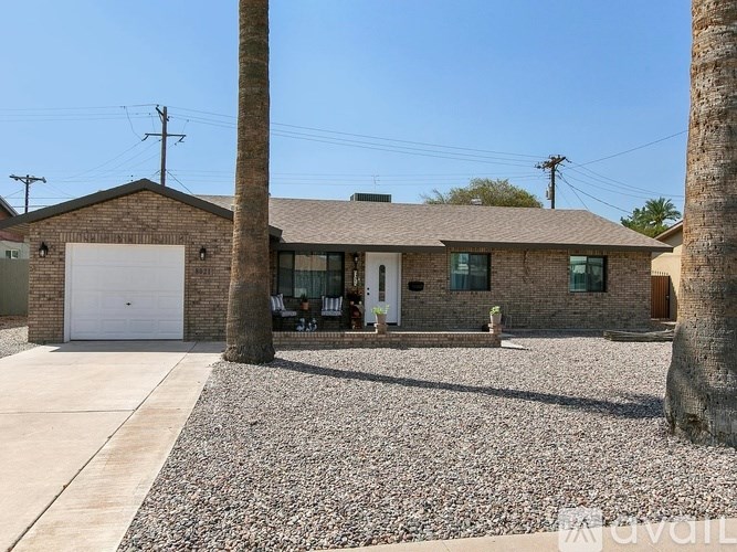 A house with a gravel driveway and two palm trees.