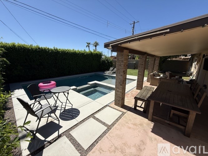 A patio with a table and chairs is surrounded by a pool.