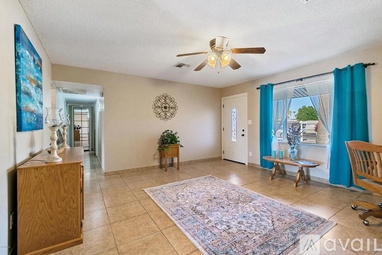 A living room with a rug, a ceiling fan, and a wooden cabinet.