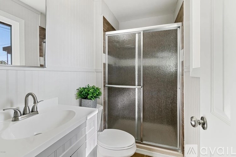 A white bathroom with a toilet, sink, and shower.