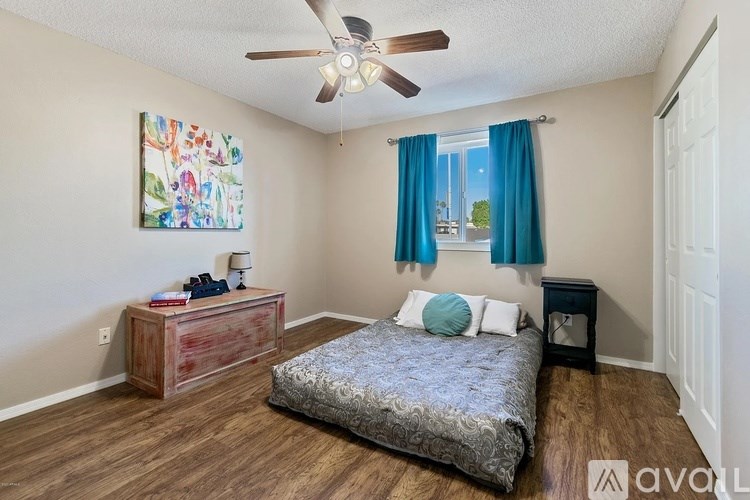 A bedroom with a bed, a dresser, and a ceiling fan.