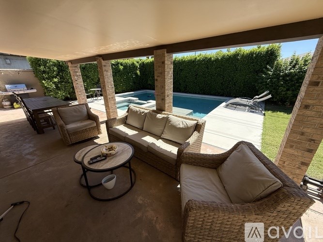 A patio with a table, chairs, and a pool in the background.