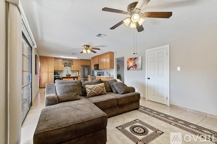 A living room with a brown couch and a ceiling fan.