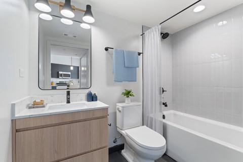 A modern bathroom with a white toilet, a white sink, and a white bathtub.