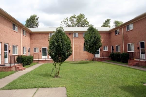 a brick building with a lawn and trees in front of it