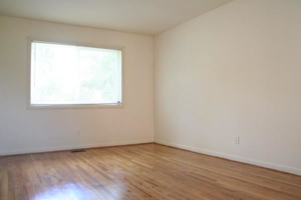 an empty room with a window and wooden floors