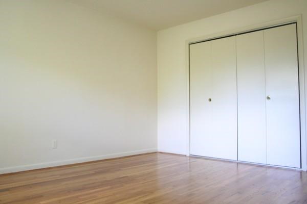 an empty room with a wood floor and a closet