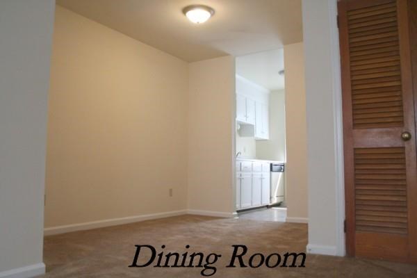 an empty dining room with a door to a kitchen