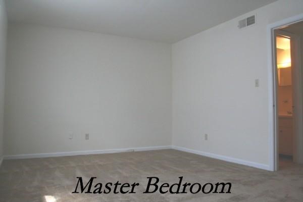 an empty room with a master bedroom and a door to the bathroom