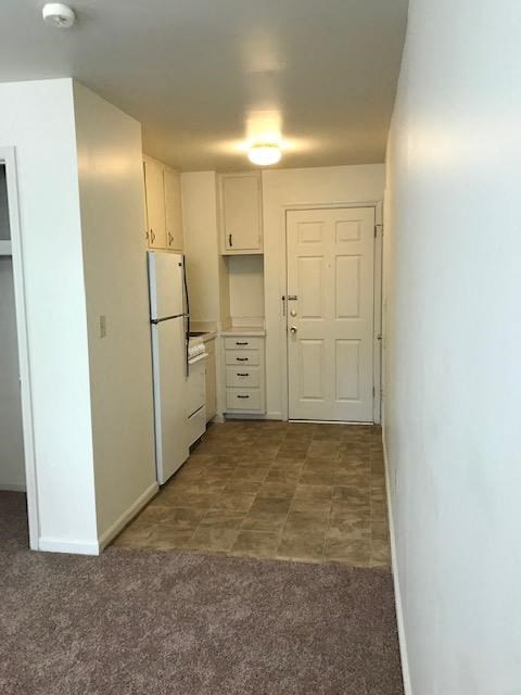 A kitchen with white cabinets and a refrigerator.